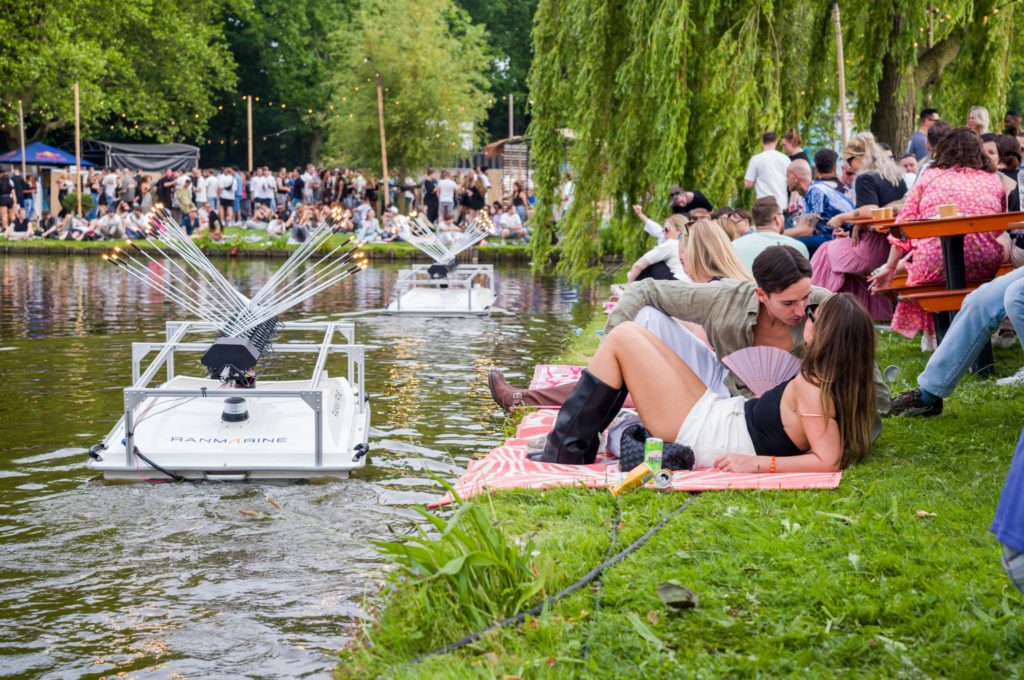 Festival goers next to the lake with WastShark and SEPIA artwork