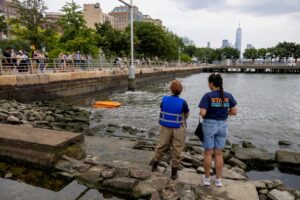 2People driving a WasteShark in a body of water, New York in the background